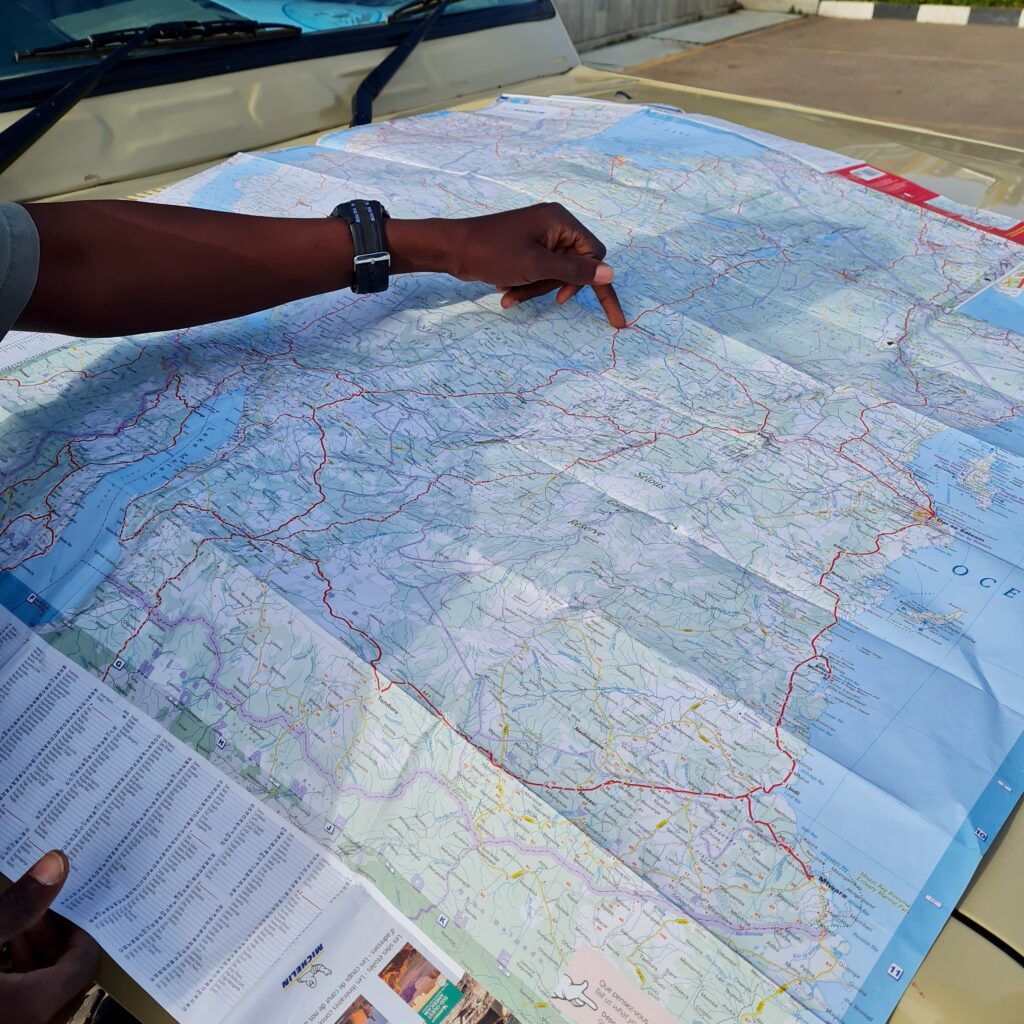 Carte de la Tanzanie avec main d'un guide maasai indiquant les parcs de safari près d'Arusha.