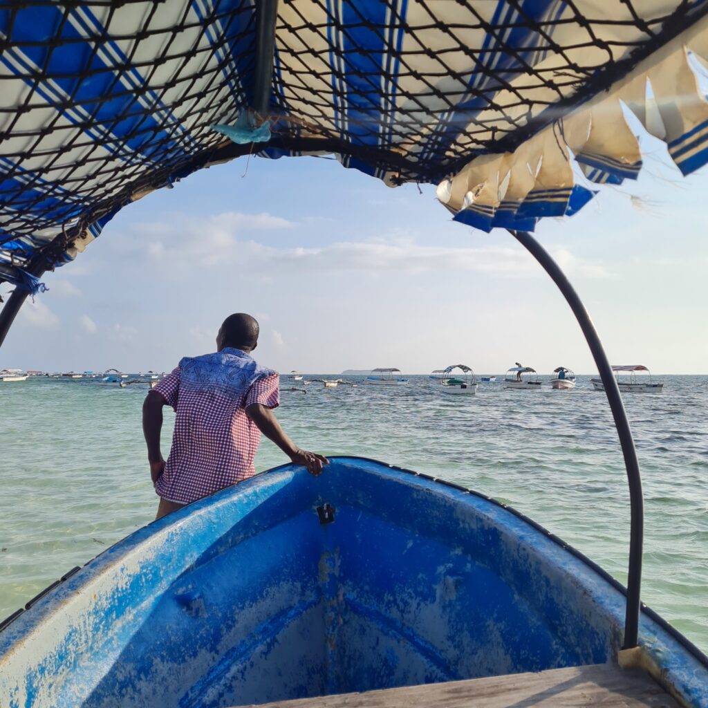 Tanzanien tirant un bateau bleu sur une plage de Zanzibar en Tanzanie.